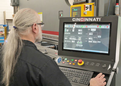 Operating the computer numeric controls (CNC) on a five-axis press brake with a 14-foot bed.